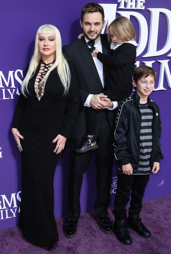 Christina Aguilera channels Morticia Addams in a long black lace-up gown and platform heels, posing with fianc&eacute; Matthew Rutler and their children, Summer Rain and Max Bratman, at The Addams Family premiere