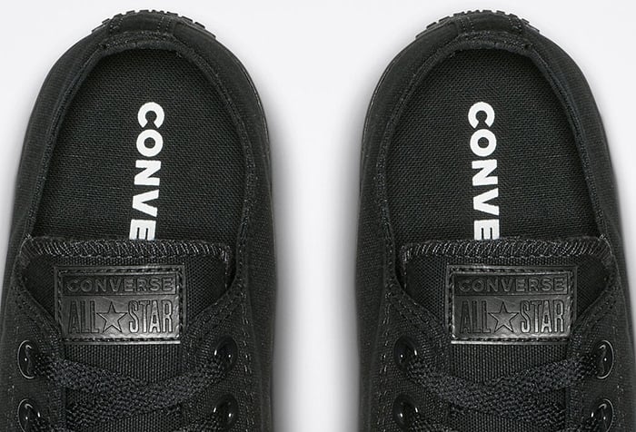 Authentic black monochrome Converse Chuck Taylor All Star sneakers featuring tonal &ldquo;CONVERSE&rdquo; insoles and matching black logo patches