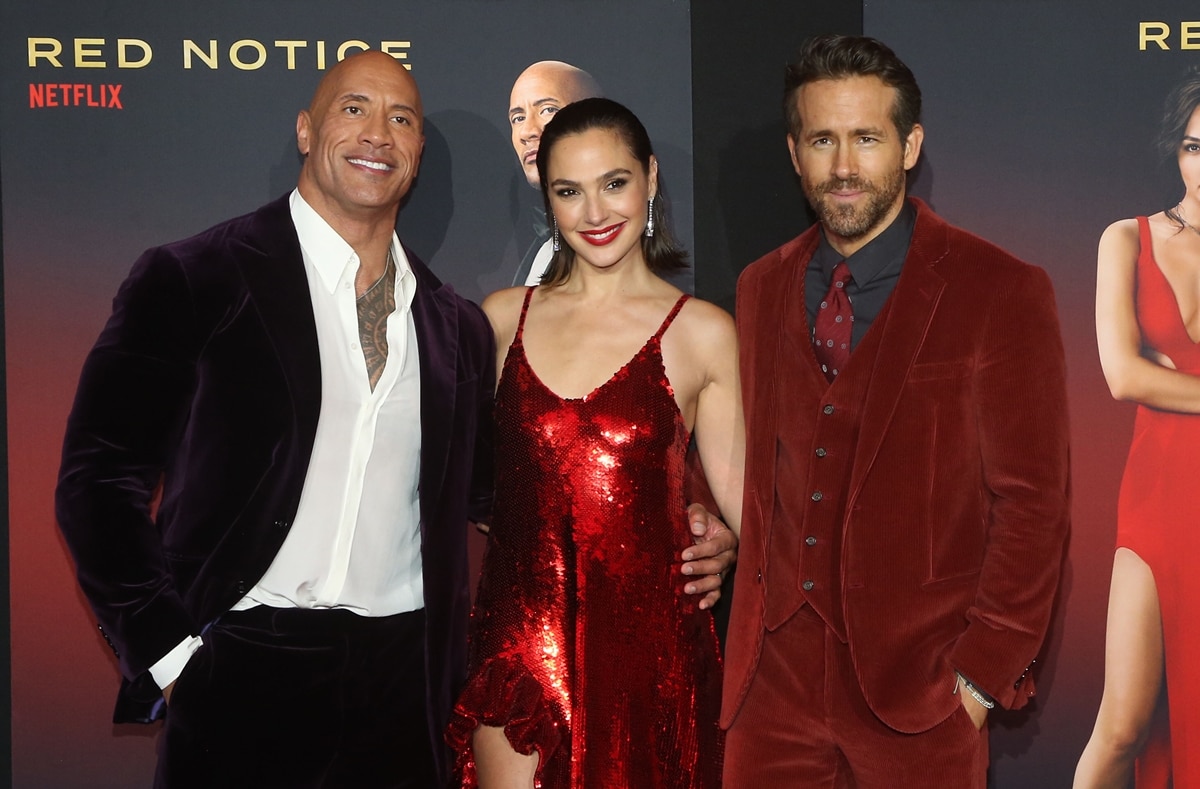 Dwayne Johnson, Gal Gadot, and Ryan Reynolds pose together at the Red Notice premiere, bringing coordinated velvet and sequins to L.A. Live in Los Angeles on November 3, 2021