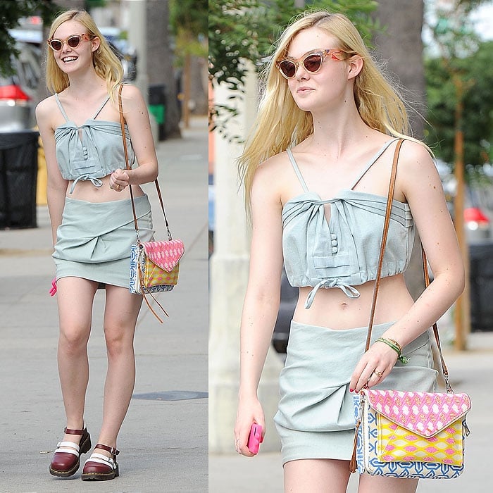Elle Fanning shows off her midriff in a playful denim crop top and skirt, accessorized with a colorful Rebecca Minkoff bag and Dr. Martens x Agyness Deyn shoes