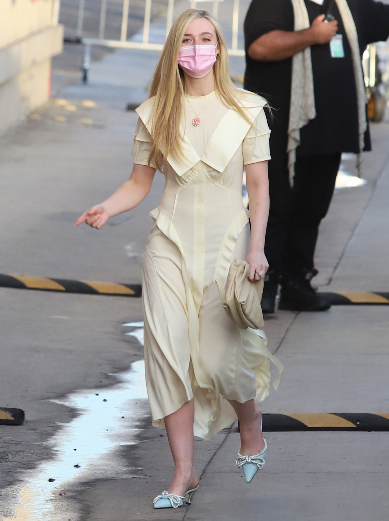 Elle Fanning heads to the Jimmy Kimmel Live studio in a softly structured pale-yellow midi dress, grounding the refined daytime look with glittering blue Mach & Mach bow-embellished kitten-heel mules