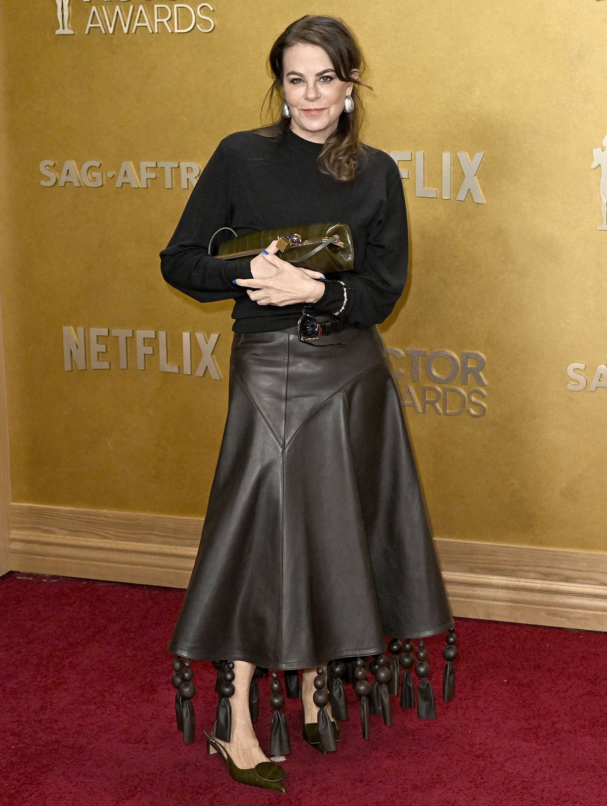 Francine Maisler pairs her geometric shoes with a brown leather Jacquemus &ldquo;The Triangle&rdquo; A-line midi skirt with oversized leather-covered balls and long leather tassels