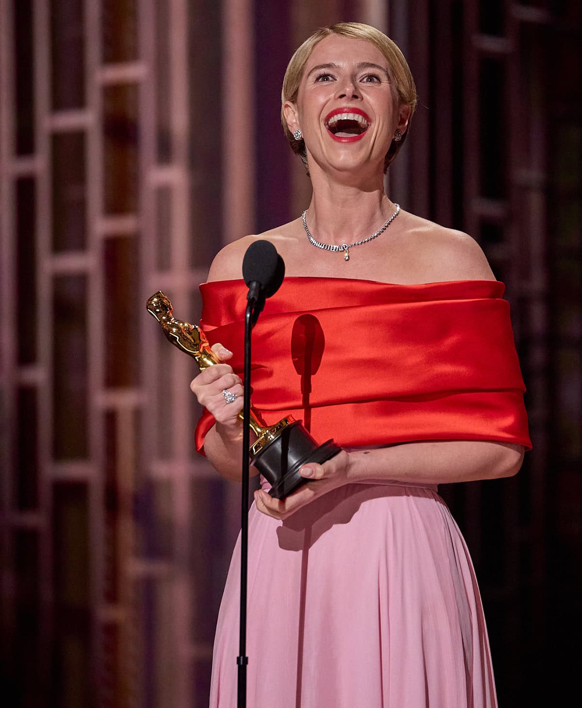 Jessie Buckley beams while accepting the Best Actress award at the 98th Academy Awards on March 15, 2026, at the Dolby Theatre in Hollywood, becoming the first Irish woman to win the category while wearing a striking red-and-pink Chanel gown