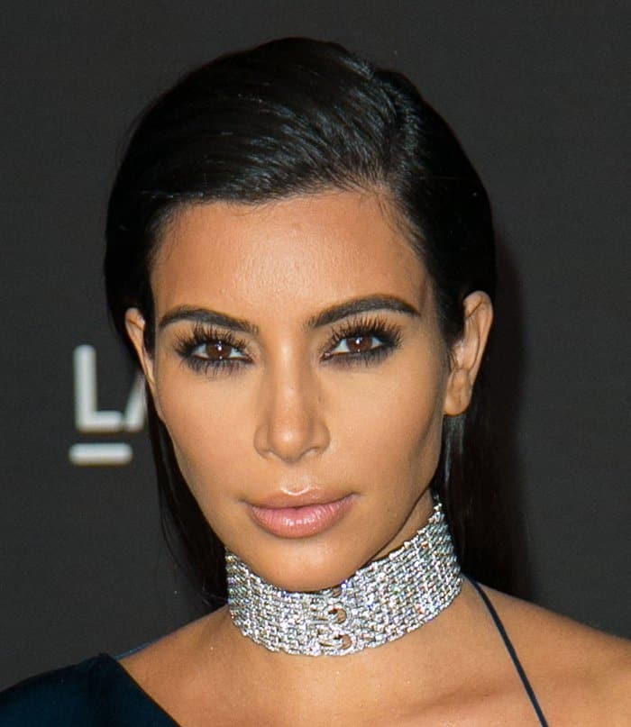 Kim Kardashian's look is completed with a sleek, center-parted hairstyle that draws attention to her exquisite diamond Cartier choker necklace