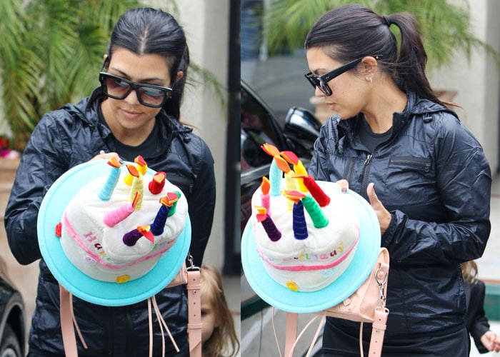 Kourtney Kardashian carries a playful &ldquo;Happy Birthday&rdquo; cake decoration