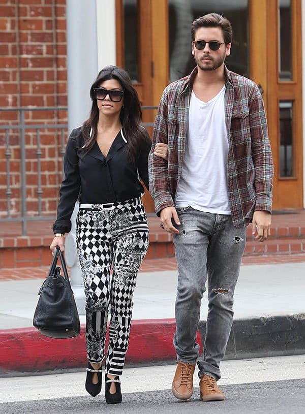 Kourtney Kardashian (5&prime; 0&Prime;) stuns in a chic black blouse and patterned pants, while Scott Disick (5&prime; 11&Prime;) rocks a casual look with torn jeans and a plaid shirt, highlighting their noticeable height difference