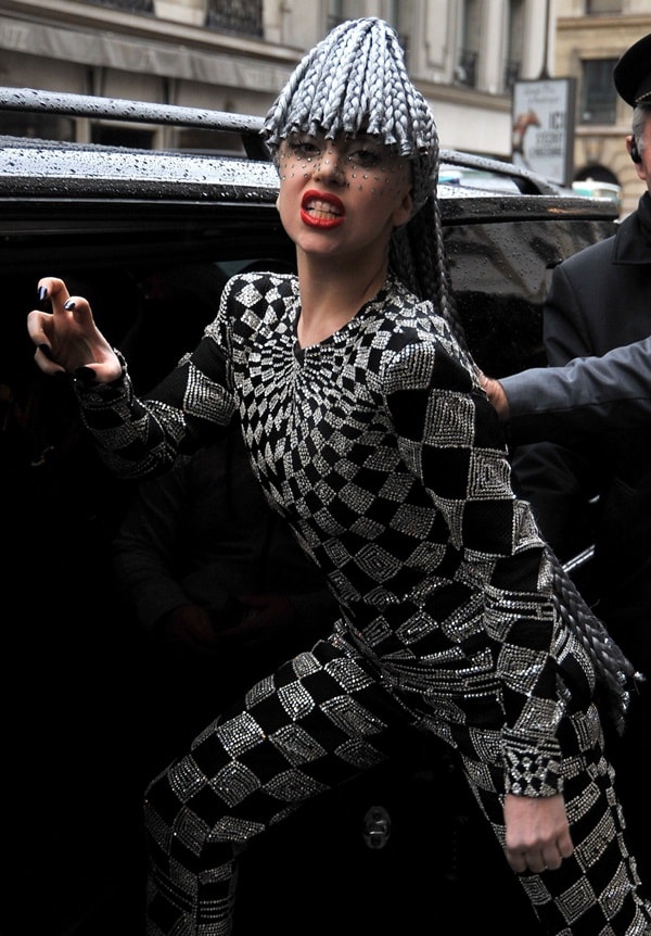 The singer channels her theatrical energy in the same vintage Versace look, striking a fierce pose that highlights the outfit&rsquo;s harlequin pattern