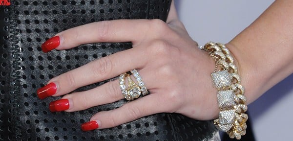A close-up of Miley Cyrus&rsquo;s hand, highlighting her breathtaking 3.5-carat diamond engagement ring from Liam Hemsworth, paired with bold red nails and a chunky gold bracelet for added edge