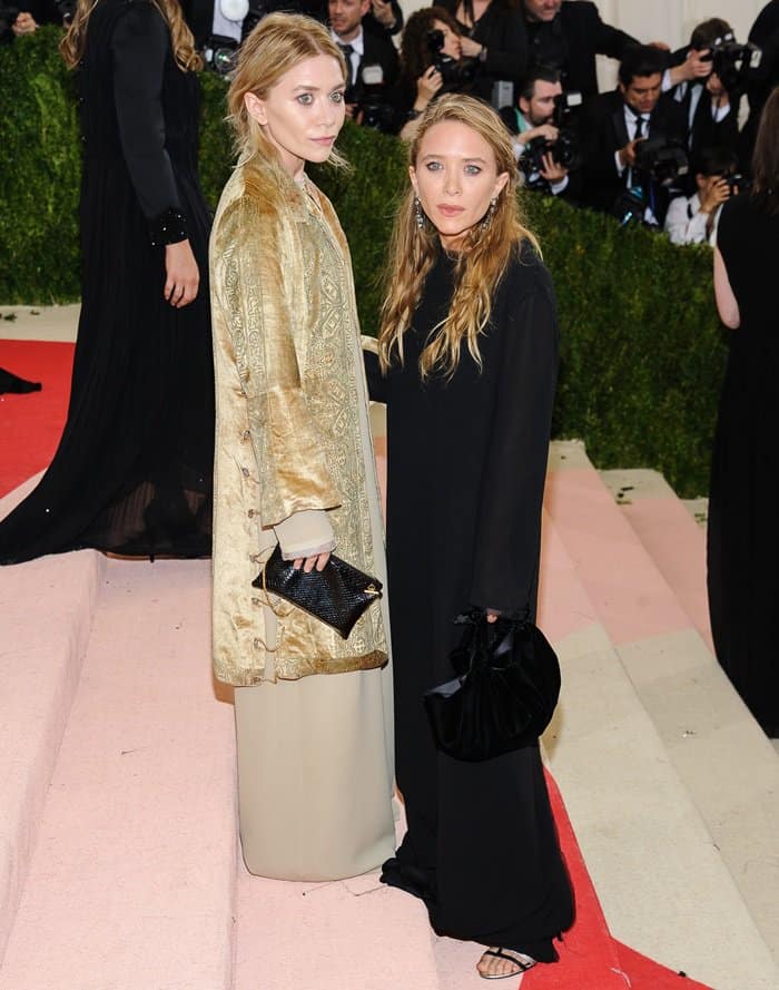 Ashley Olsen wore an embroidered gold coat layered over a neutral maxi dress, while Mary-Kate opted for a dramatic black gown styled with a plush velvet bag and strappy sandals at the Metropolitan Museum of Art Costume Institute Gala: Manus x Machina: Fashion in an Age of Technology at the Met Museum
