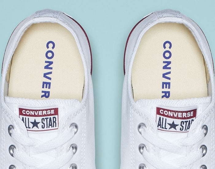 The inner soles of authentic white Converse Chuck Taylor All Star sneakers, featuring the signature navy &ldquo;CONVERSE&rdquo; print