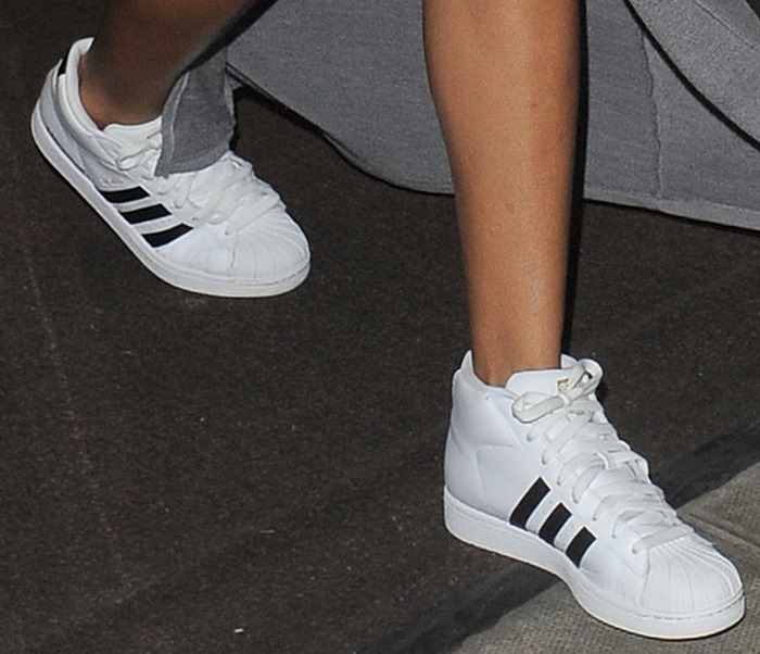 Rihanna stepped out in crisp white adidas Pro Model sneakers, featuring the brand&rsquo;s iconic shell toe and three black stripes, adding a sporty edge to her thigh-slit maxi skirt look