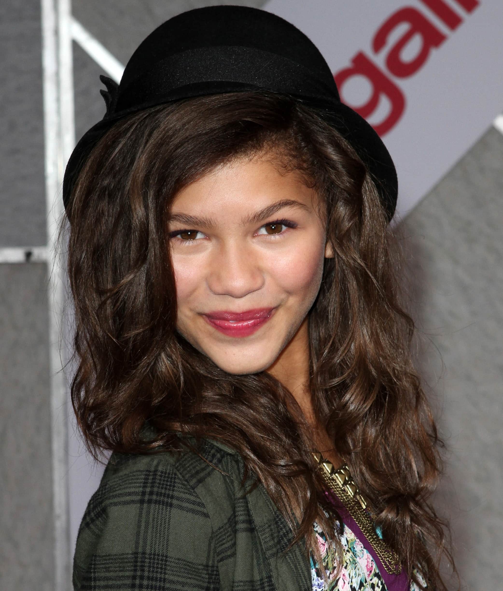 Young Zendaya showcasing her early style and youthful charm in a plaid jacket and a stylish black hat at the premiere of "You Again" at the El Capitan Theatre