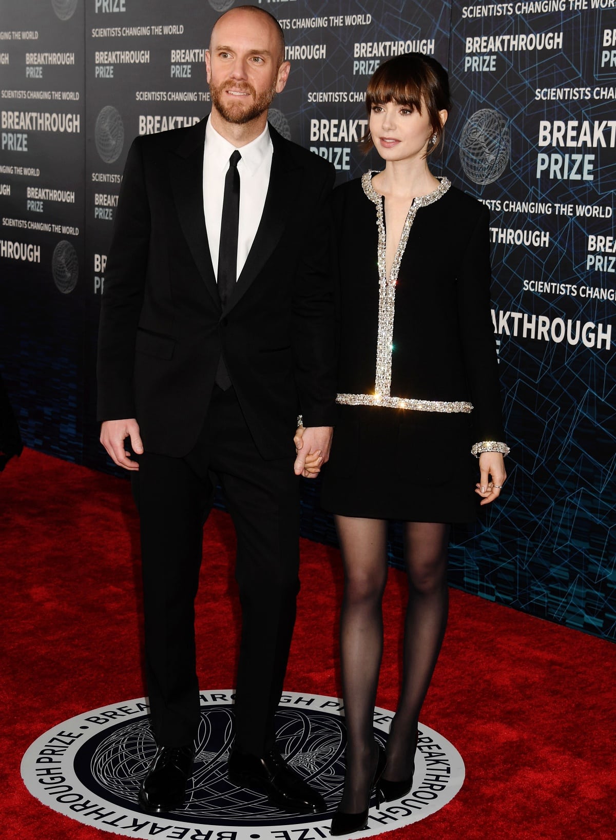Charlie McDowell complemented Lily Collins&rsquo; sleek pointed-toe pumps in a sharp black Celine suit, creating a perfectly coordinated monochrome moment on the red carpet