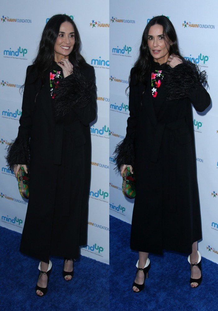 Demi Moore attends Goldie Hawn&rsquo;s Love In for Kids event in a long black coat with feather-trimmed sleeves, revealing a bright floral dress and her distinctive collar-fold black heels