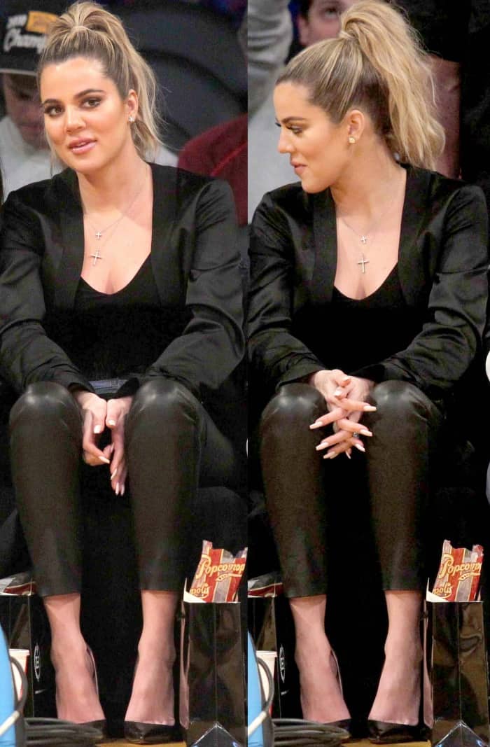 Khlo&eacute; Kardashian wearing a black jacket, a black low-cut top, black leather leggings, and black pointy-toe pumps at the Lakers vs. Cavaliers basketball game